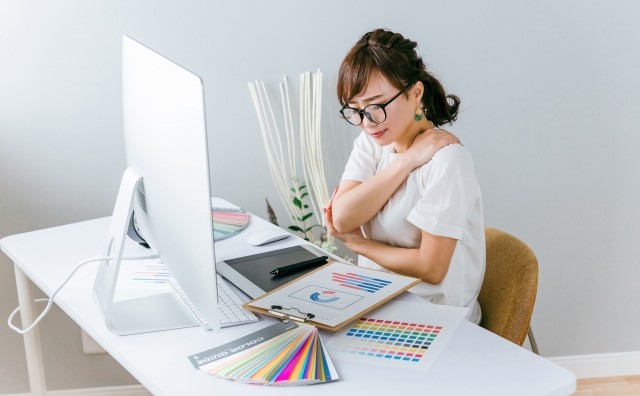 パソコン作業をしている女性。長時間の同じ姿勢による肩や首への負担の例。