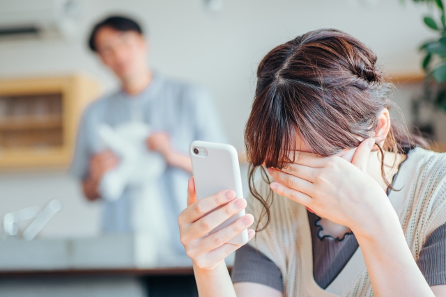 長時間スマートフォンを見て目が疲れ、頭痛を感じている女性。