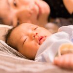 赤ちゃんの隣で優しく添い寝をしている母親の姿。産後の穏やかな育児時間の一場面。