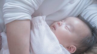 授乳が終わり赤ちゃんの隣で優しく添い寝している母親の様子