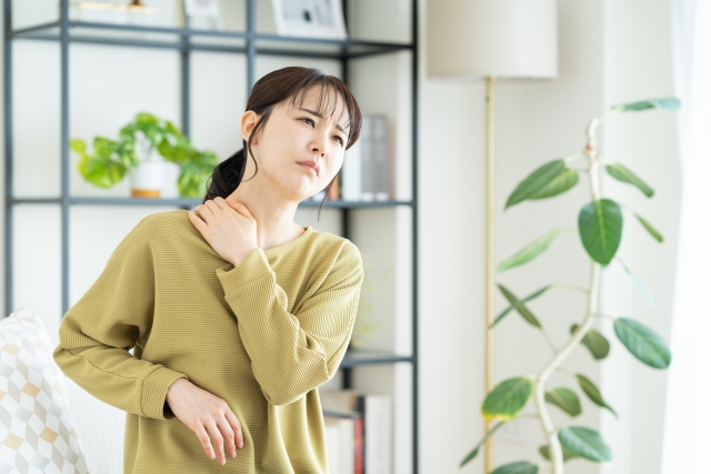 肩こりがつらく肩を押さえている女性の写真
