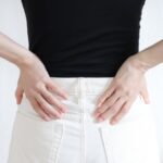 骨盤を手で押さえ、歪みを気にする女性