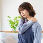 肩を手で押さえ、不快感を訴える女性