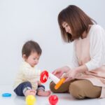 横座りで赤ちゃんと遊ぶ女性。