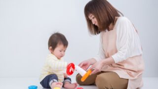 横座りで赤ちゃんと遊ぶ女性。