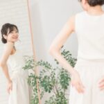 鏡に映る自分の骨盤ラインを確認しながら、笑顔を見せる女性。骨盤が安定したことで体の変化を実感している様子。