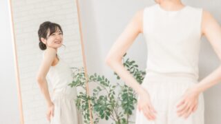 鏡に映る自分の骨盤ラインを確認しながら、笑顔を見せる女性。骨盤が安定したことで体の変化を実感している様子。