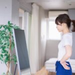 鏡の前で真剣な表情で自分の下半身をチェックする産後ママの様子。