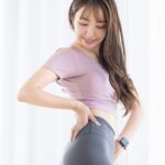 鏡の前で骨盤の位置を意識しながら体の変化を確認する女性。来月頑張るため、今のうちに体を整えようとする前向きな女性をイメージした写真。