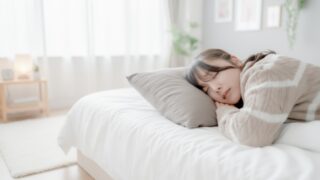 産後の女性がベッドで寝返りを打つ様子。骨盤のゆがみによる腰の違和感を感じているイメージ写真。
