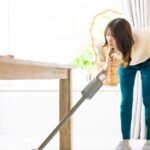 年末に中腰で掃除機をかける女性。