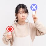 産後のNG習慣の説明のために、OKとNGプラカードを持つ女性