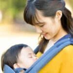 抱っこ紐で赤ちゃんと散歩をする女性
